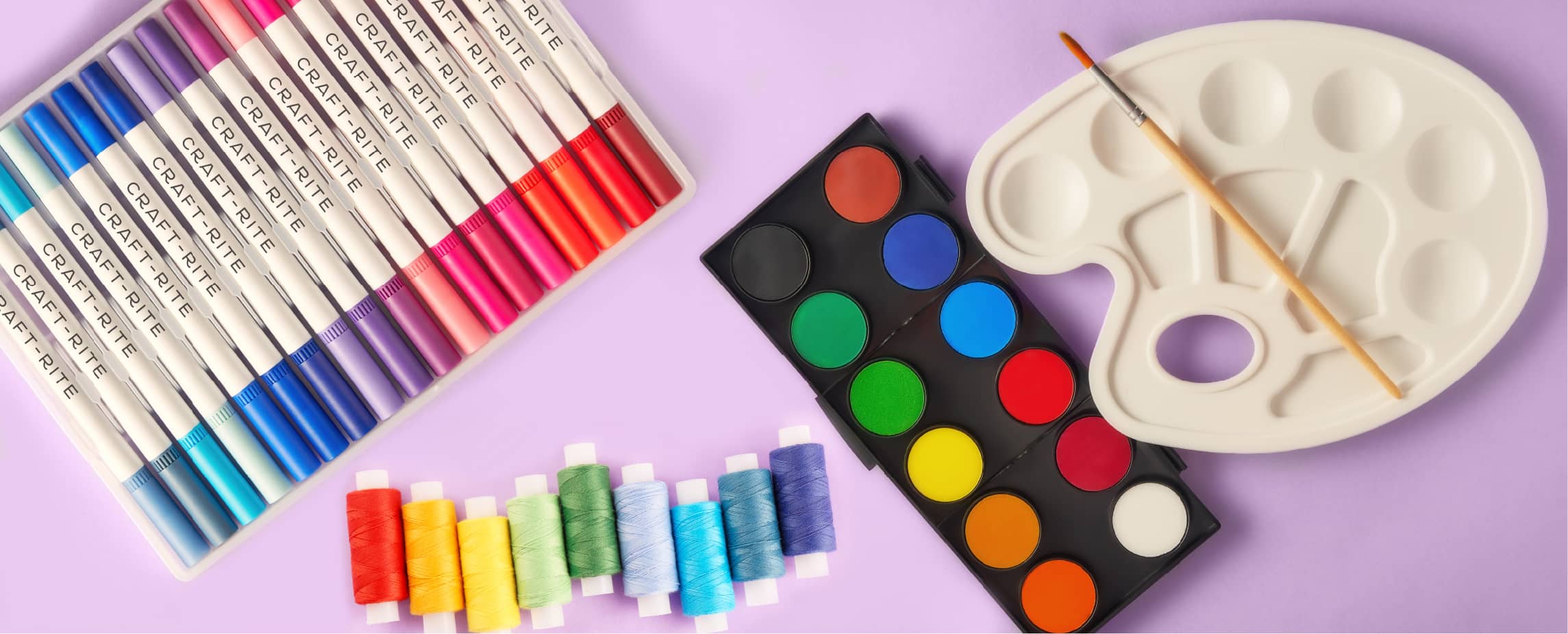 A marker set, colorful thread, paint, and paint palette with paint brush